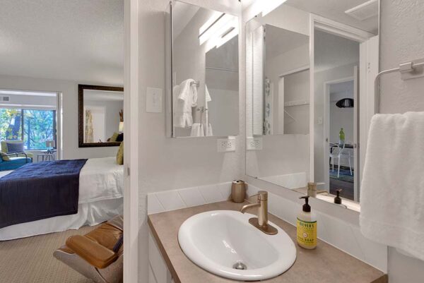 Bathroom with gold finishes, dark tan countertops, and white walls.