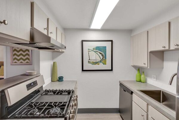 The kitchen with white cabinets, gray countertops, white walls, and art on the walls.