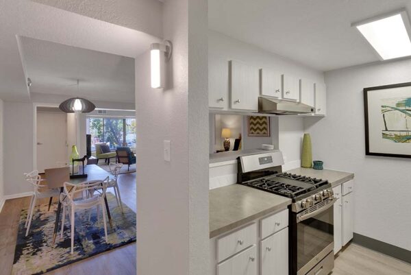 The kitchen with white cabinets, gray countertops, white walls, and art on the walls.