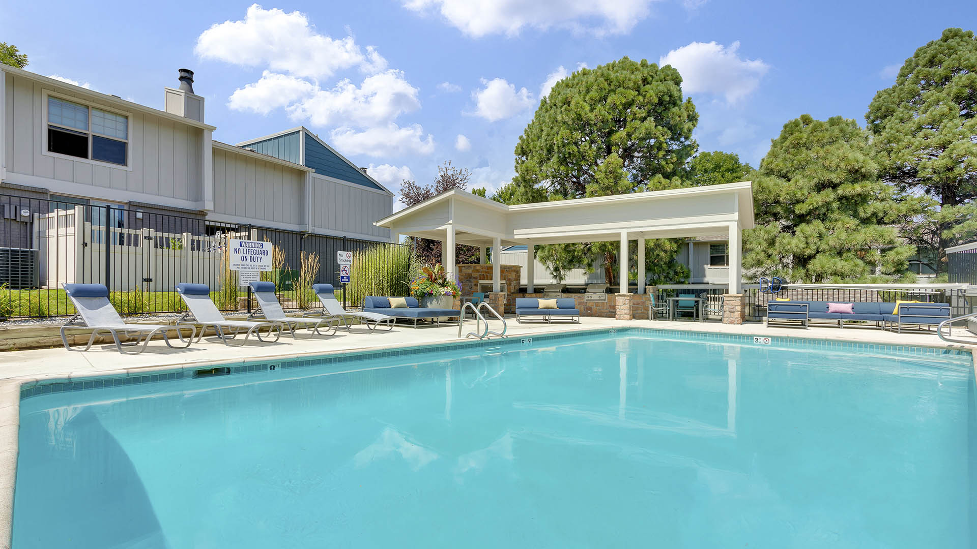 The Pines at Pinehurst pool area with comfortable lounge chairs and shady gazebo.