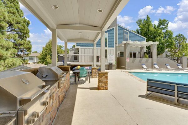 BBQ area with gazebo, dining tables, and lounge chairs next to pool.