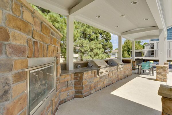 BBQ area with built in grills, stone fireplace, gazebo, and dining tables.