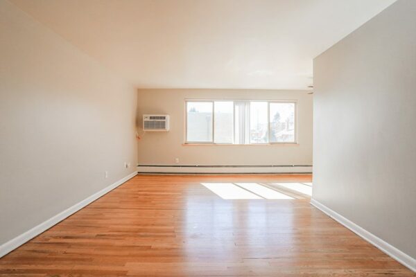 Living room with wood floor, warm grey walls, baseboard heaters, and large windows.