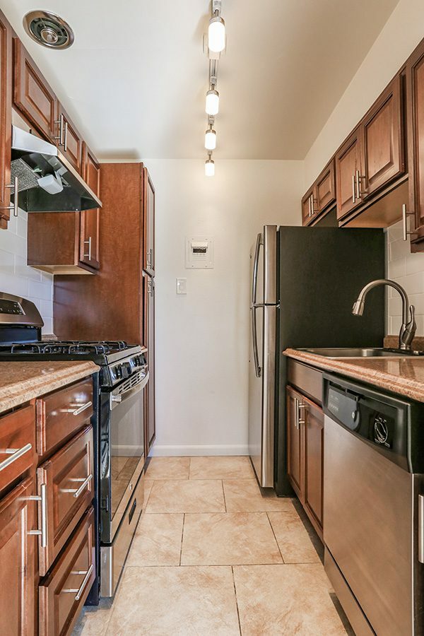 Kitchen with tile floor, wood cabinets, stone counters, and stainless steel appliances.