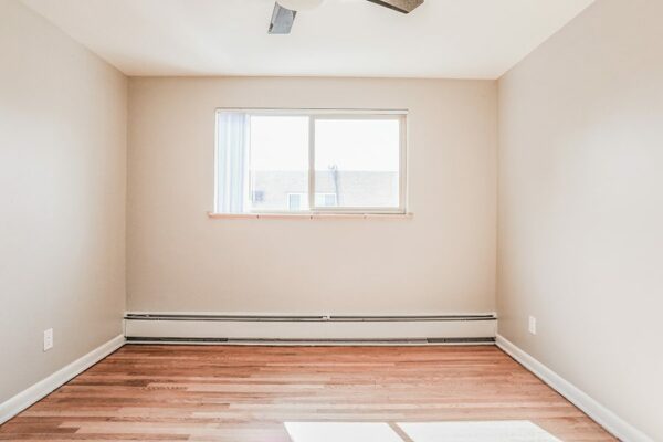 Living room with wood floor, warm grey walls, baseboard heaters, and large windows.