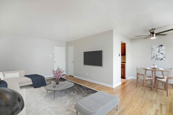 Living room with wood floor, modern furniture, ceiling fan, and door to kitchen.