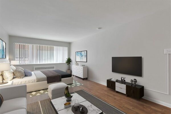 Studio living area with wood floor, plush bed, modern furnishings, and large windows.