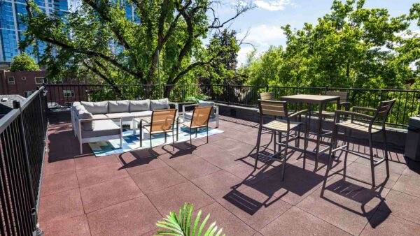 Rooftop patio with plush outdoor furniture, railings with string lights, and large plants.