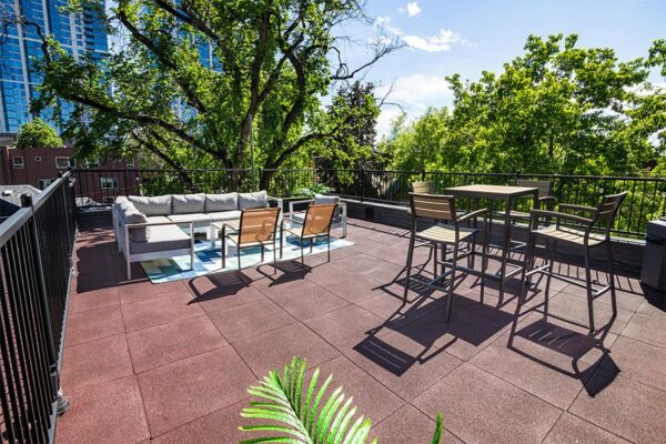 Rooftop patio with plush outdoor furniture, railings with string lights, and large plants.