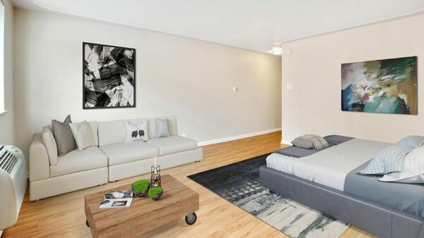 Studio living space with wood floor, plush couch and bed, wood coffee table, and large artwork.