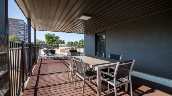 Rooftop patio with dining tables, lounge chairs, and metal railing.