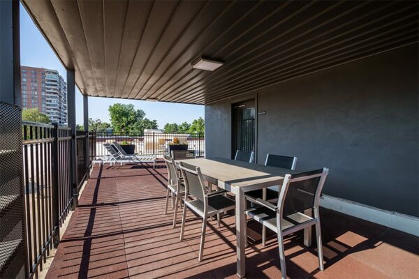 Rooftop patio with dining tables, lounge chairs, and metal railing.