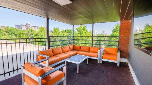 Rooftop patio with plush orange outdoor seats and TV.