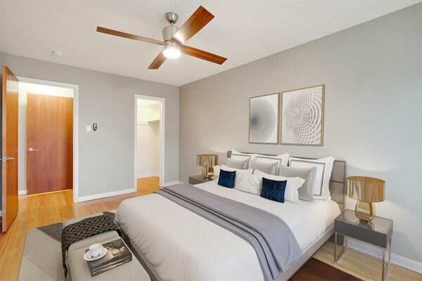 Bedroom with plush bed, dressing table, bedside tables with lamps, and artwork.