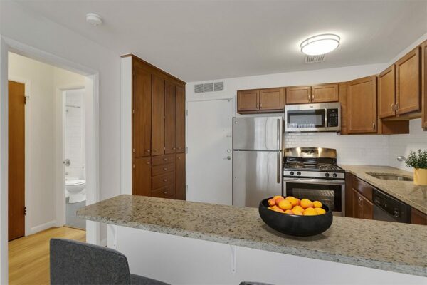 Kitchen with a bowl of fruit on the peninsula, stainless steel appliances, and dark wood cabinets.