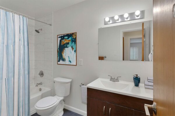 Bathroom with dark wood cabinets, white countertops, and a full-sized shower.