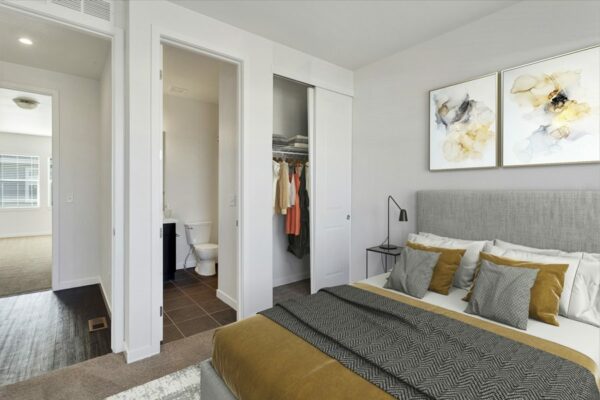 Rendering of a bedroom with an attached bathroom, closet, and white walls.