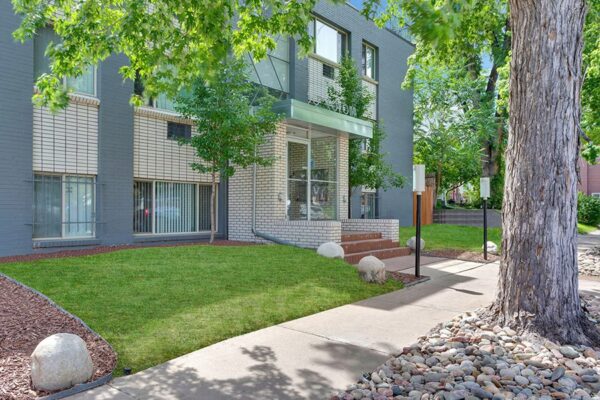 50 Corona apartments with grey brick construction, art deco styling, and lush landscaping.