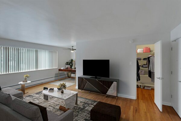 Living room with TV console, plush couch, and large windows.
