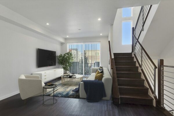 Rendering of stairs leading down into a living room with wood floors and patio doors.