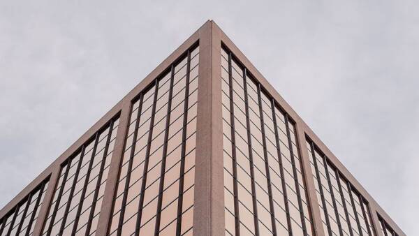 Symmetrical image of office tower with rose gold reflective windows.