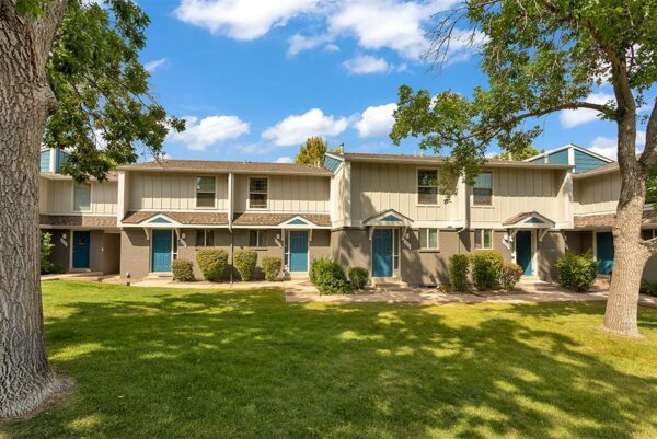 Exterior view of The Pines at Pinehurst apartment buildings with grass and trees.
