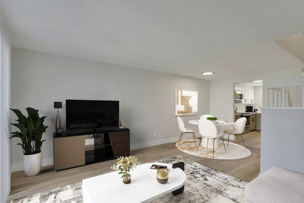 Living area with wood floors, white walls, and a dining area.