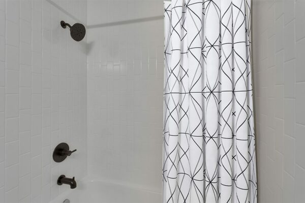 A shower with white tiles and black fixtures.
