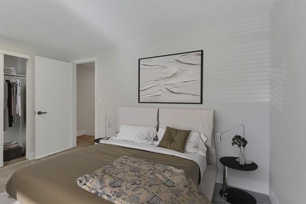Bedroom with a closet, white walls, and tan carpet.