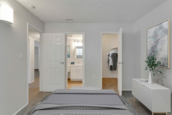 Bedroom with tan carpet, a large closet, and a connected bathroom.