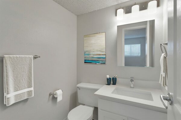Bathroom with white cabinets & countertops, and white walls.