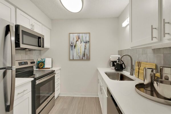 Rendering of a kitchen with white cabinets & countertops, stainless steel appliances, and wood floors.