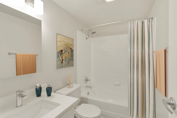Rendering of a bathroom with a full-sized tub, white cabinets & countertops, and art work on the walls.