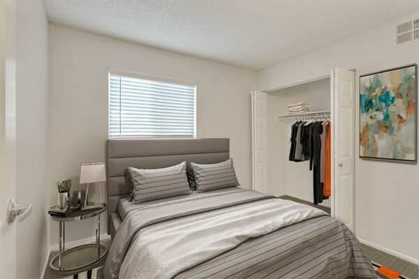 Rendering of a bedroom with tan carpet, a closet, and white walls.