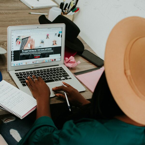 Person in hat working on laptop computer.