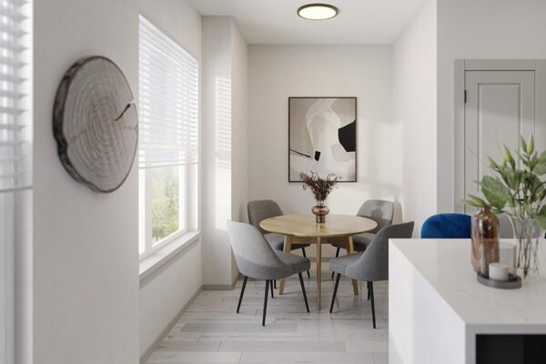 Dining area with round table, plush chairs, large window, and framed art.