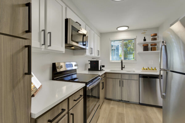 Kitchen with wood floors, stainless steel appliances, and white countertops.