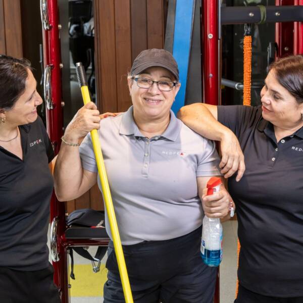 three woman handing close to each other, one holding a mop and cleaner in the middle