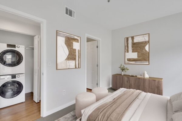 one bedroom with bed in middle, dresser, and two large windows with view of washer and dryer in hallway