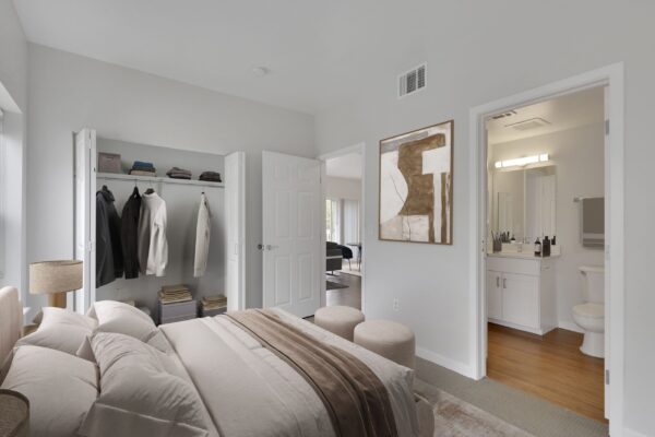 one bedroom with bed in middle, dresser, and two large windows with view of bathroom
