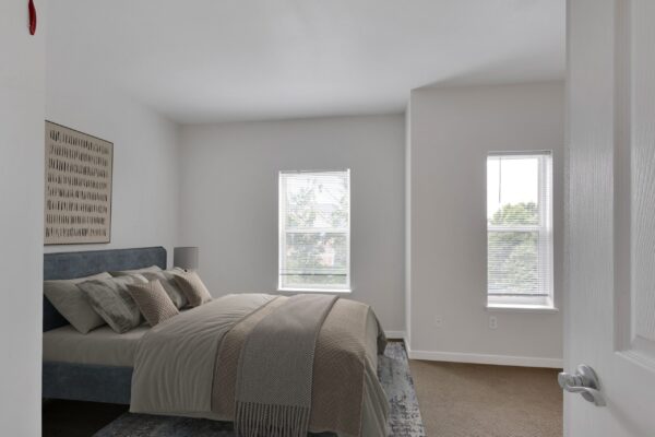 one bedroom with two large windows and bed
