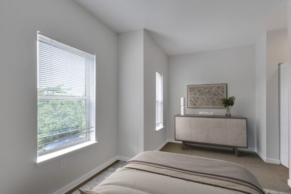 one bedroom with two large windows and bed and dresser