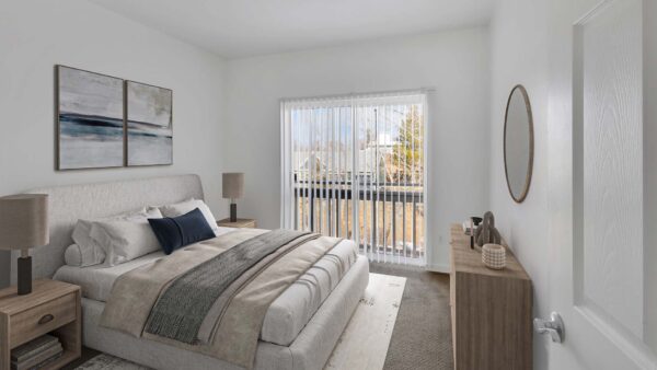 Bedroom with carpet, plush bed with headboard, bedside tables with lamps, and sliding balcony door.