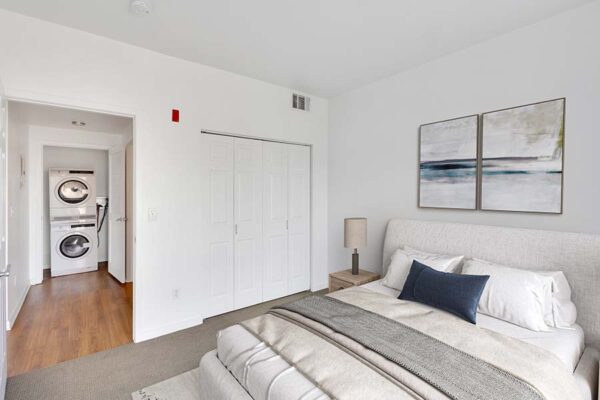 Trocadero apartment bedroom with plush bed, headboard, framed artwork, and large closet.