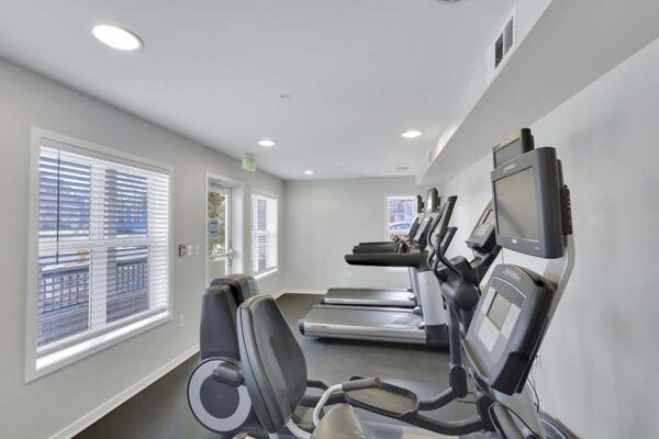 Trocadero apartments fitness center with cardio machines and large windows.