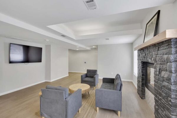 Trocadero apartments lounge with plush seating, wall mounted TV, and fireplace.