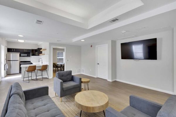 Trocadero apartments lounge with plush seating, community kitchen, and wall mounted TV.
