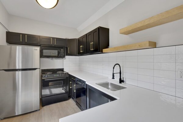 Trocadero apartments kitchen with dark cabinets, light counters, and stainless steel appliances.