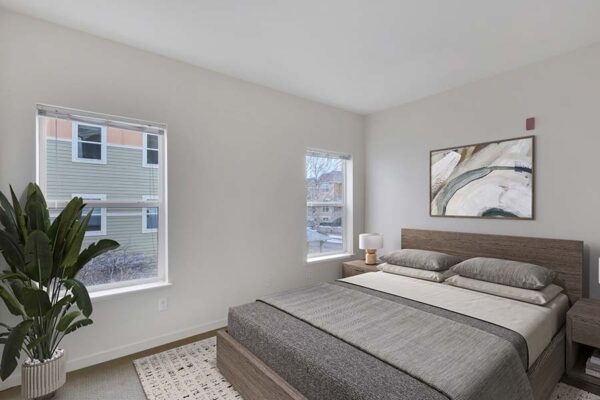 Trocadero apartment bedroom with carpet, wood bed with headboard, framed art, and large artwork.