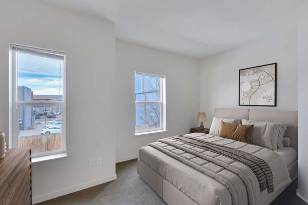 Trocadero apartment bedroom with carpet, plush bed with headboard, framed artwork, and large windows.
